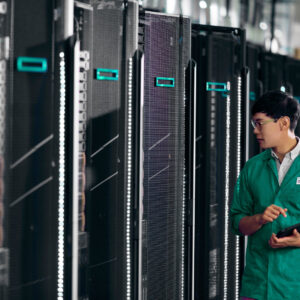 JFM Technology Tech wearing a green coat inspecting a row of server racks in a data center holding a tablet